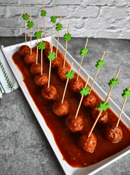 Guinness-style meatballs in rich sauce, served with shamrock toothpicks as Irish party food for a St. Patrick’s Day celebration.