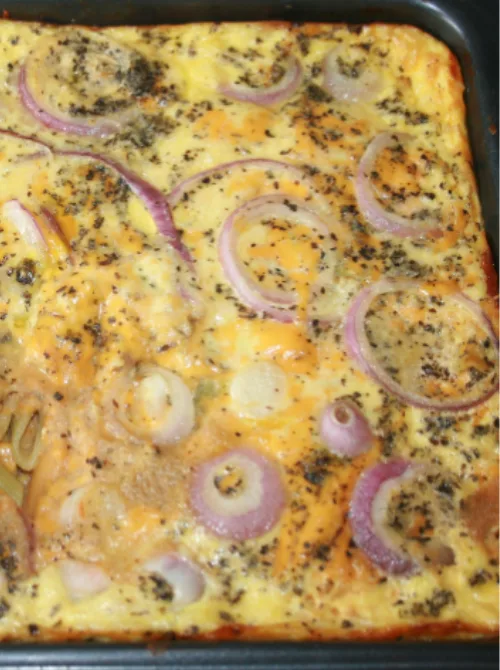Cheesy baked casserole topped with sliced red onions and herbs in a rectangular pan, a cozy example of super easy casseroles and hearty family dinner ideas.