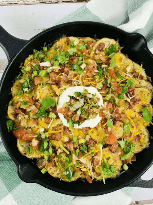 Skillet Irish nachos made with sliced potatoes, melted cheese, bacon, and fresh herbs, served as hearty Irish party food for a St. Patrick’s Day gathering.