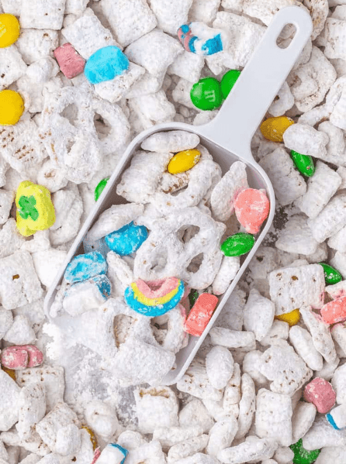 Powdered sugar muddy buddies snack mix with rainbow candies, easy no-bake St. Patrick’s Day dessert on a budget.