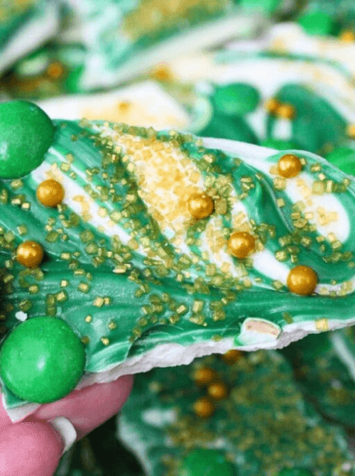 Green and white no-bake candy bark topped with gold sprinkles and green candies, festive St. Patrick’s Day dessert on a budget.