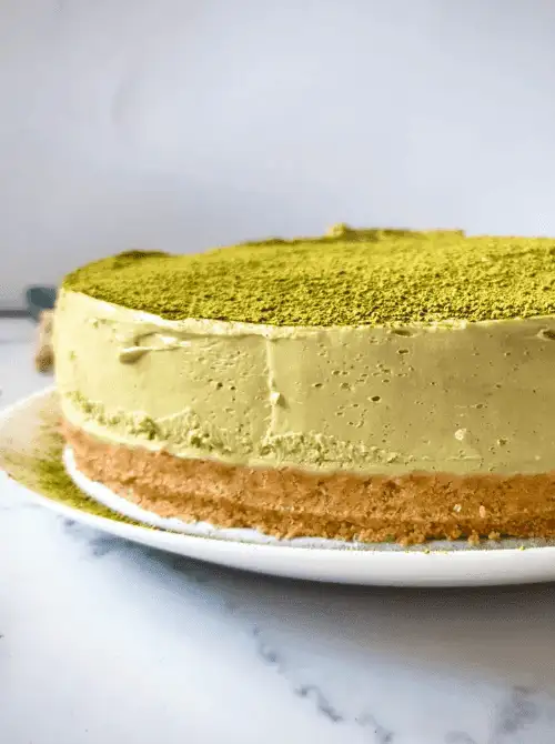 Matcha cheesecake with a graham-style crust on a white plate, shown as a make-ahead dessert for St. Patrick’s Day and desserts on a budget.