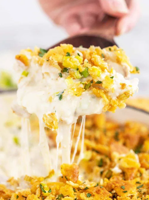 Close-up of a spoon lifting a cheesy chicken casserole with a creamy, stretchy center and crispy topping, highlighting chicken casseroles that work well for easy weeknight dinners.