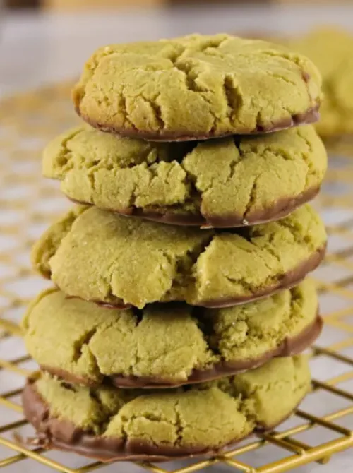 Stack of soft pistachio cookies dipped in chocolate on a cooling rack, featured in festive St. Patrick’s Day Dessert Ideas for a cozy party spread. 🍀