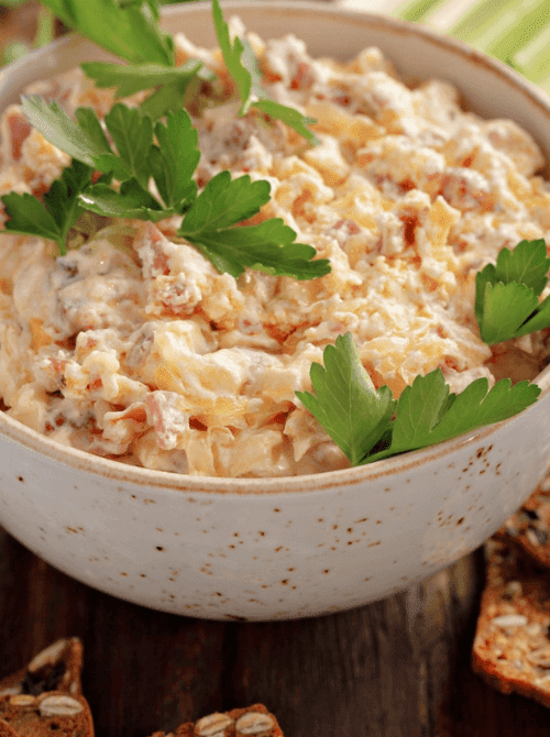 Creamy Reuben dip with corned beef, cheese, and sauerkraut, garnished with parsley as Irish party food for a St. Patrick’s Day gathering.