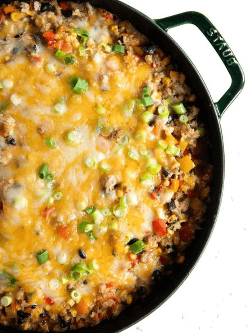 Cheesy ground beef and vegetable skillet casserole topped with green onions in a cast iron pan, a hearty example of super easy casseroles and satisfying family dinner ideas.