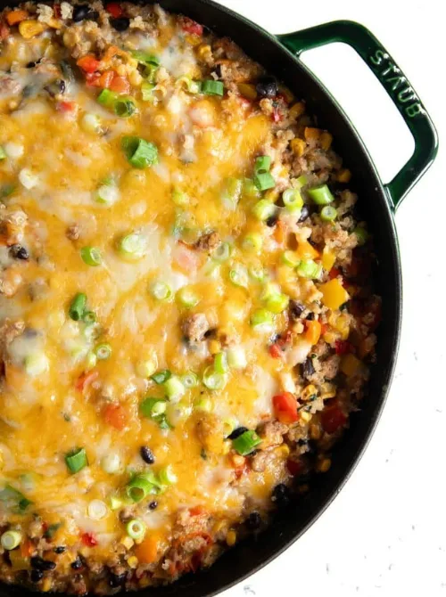 Cheesy ground beef and vegetable skillet casserole topped with green onions in a cast iron pan, a hearty example of super easy casseroles and satisfying family dinner ideas.