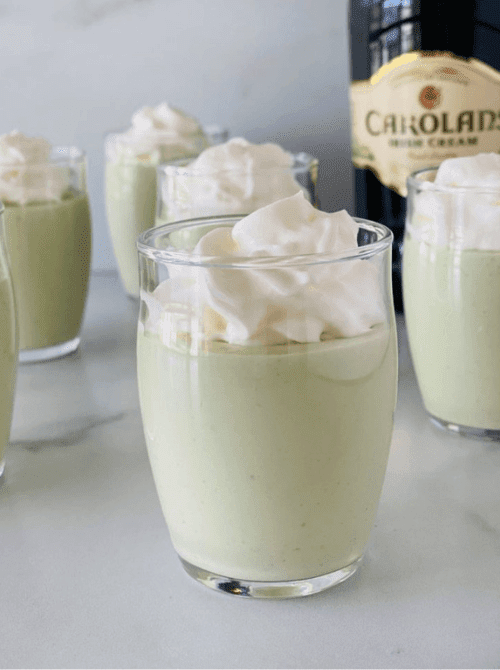 Mini mint dessert cups with whipped cream, simple St. Patrick’s Day party treat for adults.