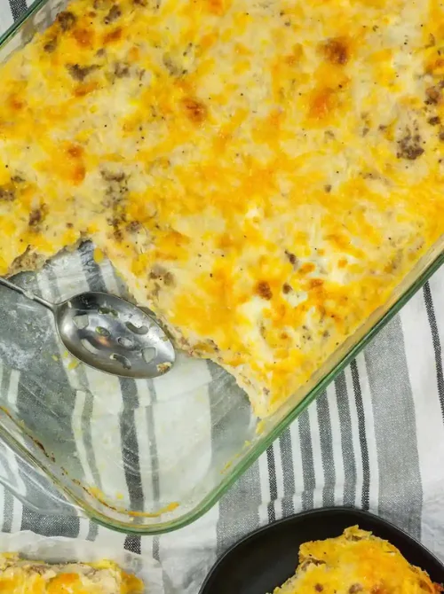 Cheesy sausage and egg breakfast casserole baked in a glass dish with a slice removed, a hearty family favorite often included in make-ahead Easter brunch casseroles.