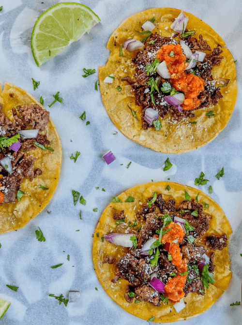 Crispy beef smash tacos on yellow corn tortillas topped with charred ground chuck, homemade hot sauce, red onion, cotija cheese, and fresh cilantro — an easy Cinco de Mayo party food recipe for a crowd that makes 10 tacos in under 30 minutes of active cooking time.