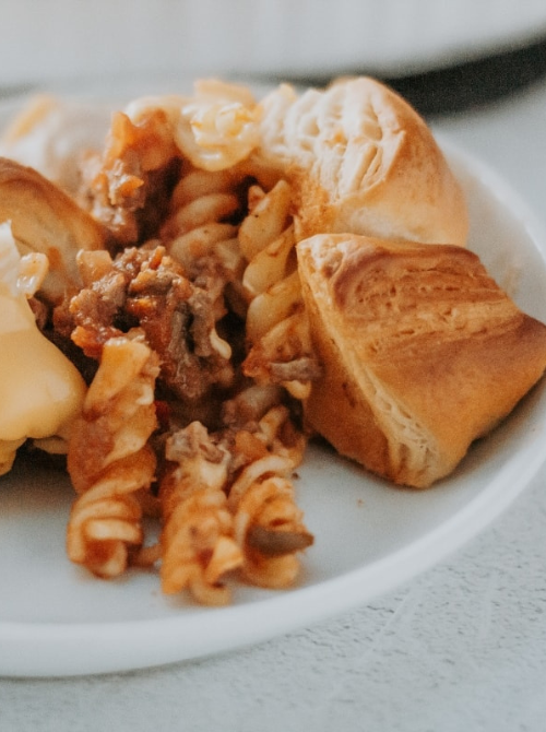 Pasta casserole wrapped in golden baked dough with ground beef and melted cheese, a creative comfort casseroles idea for easy comfort food and recipes for busy nights.