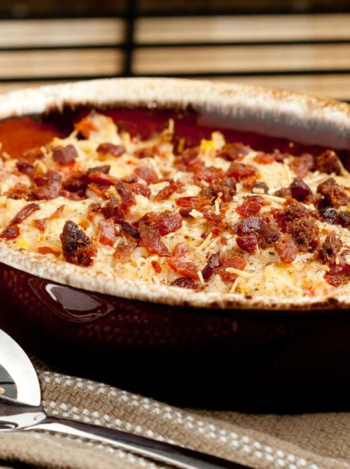 Creamy baked breakfast casserole topped with crispy bacon and melted cheese in a ceramic baking dish, a comforting choice for make-ahead Easter brunch casseroles.