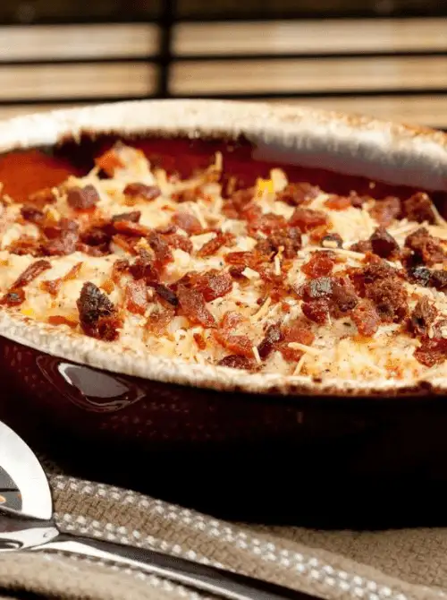 Creamy baked breakfast casserole topped with crispy bacon and melted cheese in a ceramic baking dish, a comforting choice for make-ahead Easter brunch casseroles.