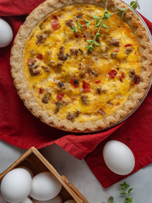 Savory sausage and pepper quiche baked in a flaky pie crust with herbs on top, a flavorful option often included in make-ahead Easter brunch casseroles for a festive holiday table.