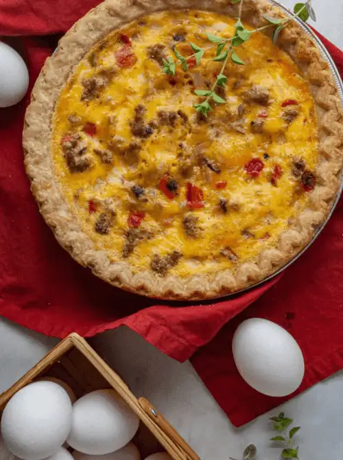 Savory sausage and pepper quiche baked in a flaky pie crust with herbs on top, a flavorful option often included in make-ahead Easter brunch casseroles for a festive holiday table.