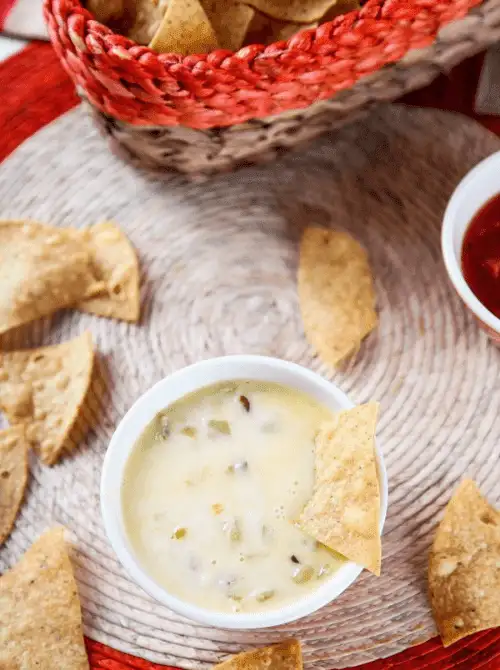 Creamy homemade queso blanco in a white bowl surrounded by tortilla chips — an easy Cinco de Mayo party food recipe for a crowd that's ready in under 10 minutes and tastes like a restaurant copycat.
