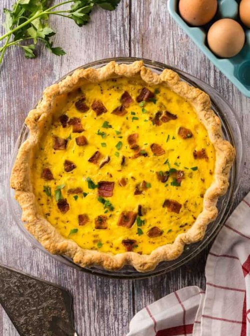 Golden quiche with bacon and fresh herbs in a flaky crust, a classic savory option often featured in make-ahead Easter brunch casseroles for an easy holiday meal.