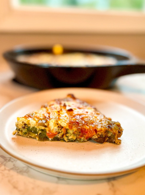 Slice of vegetable and egg breakfast casserole with melted cheese served on a plate, a savory and hearty option for make-ahead Easter brunch casseroles.