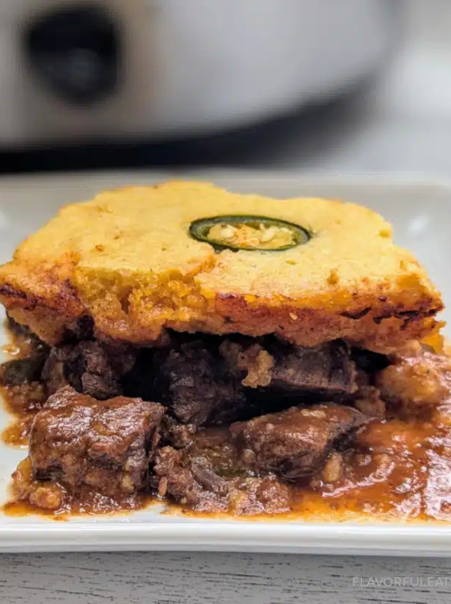 Hearty beef casserole topped with golden cornbread and a slice of jalapeño, a filling comfort casseroles dish for easy comfort food and recipes for busy nights.