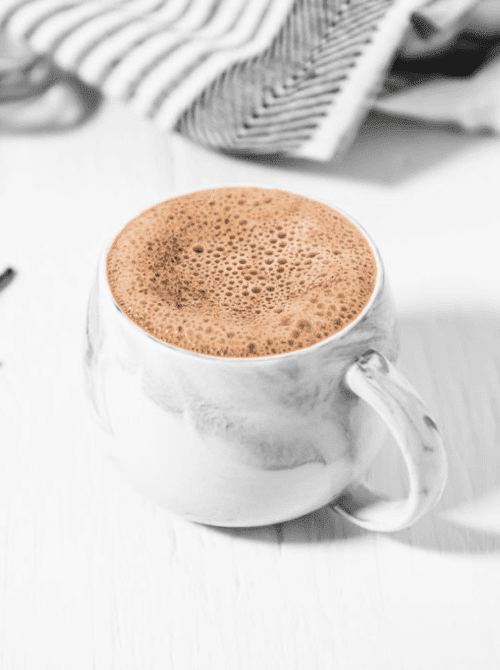 A frothy homemade French vanilla cappuccino in a marble mug on a white surface — a caffeine-free instant drink mix that makes a cozy handmade gift for DIY Mother's Day gift baskets.