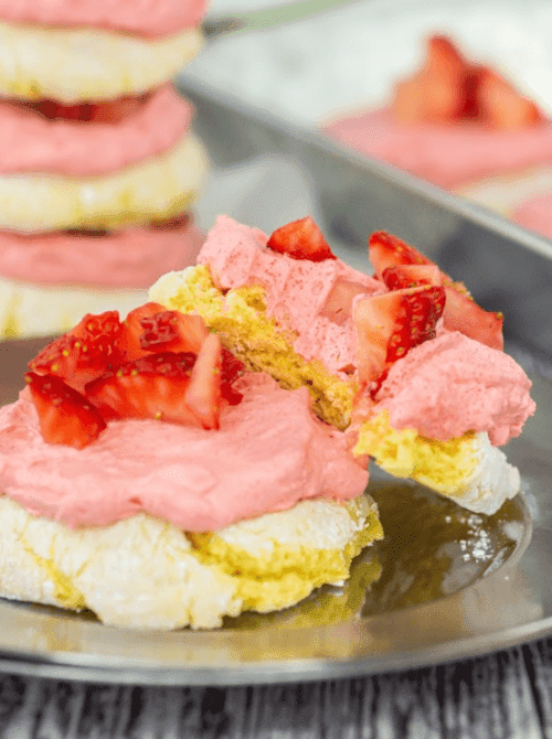 A lemon strawberry Cool Whip cookie sandwich split open on a metal tray showing layers of fluffy pink strawberry frosting and fresh diced strawberries — a bright and budget-friendly thing to make with strawberries when you need dessert fast.